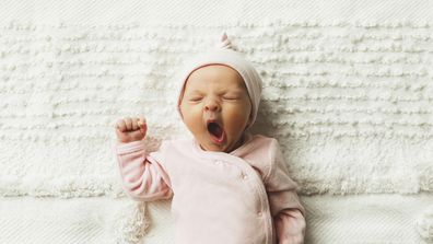 A close-up of an adorable baby girl, 4.5 weeks old, yawning. 