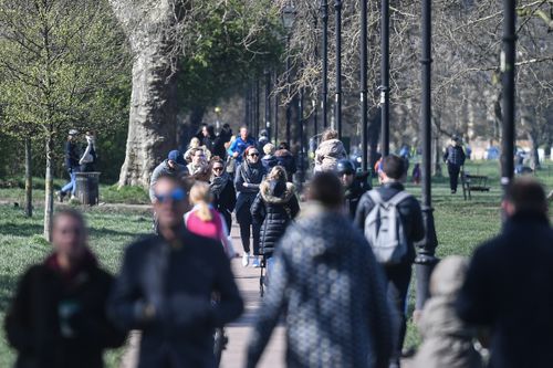 People are seen walking on Clapham Common on March 22, 2020 in London, despites social distancing warnings.