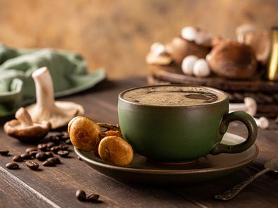 Mushroom coffee in green cup on wooden background. New Superfood trendy healthy concept with copy space, selective focus.