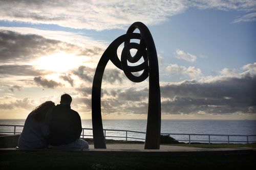 Two people embrace in the early hours of the morning at the Bali Bombings memorial shrine at Coogee Beach