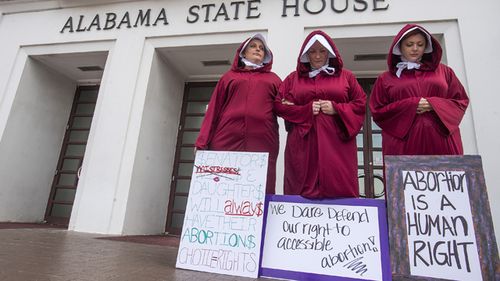 Bianca Cameron-Schwiesow, from left, Kari Crowe and Margeaux Hardline, dressed as handmaids, take part in a protest against HB314, the abortion ban bill, at the Alabama State House in Montgomery