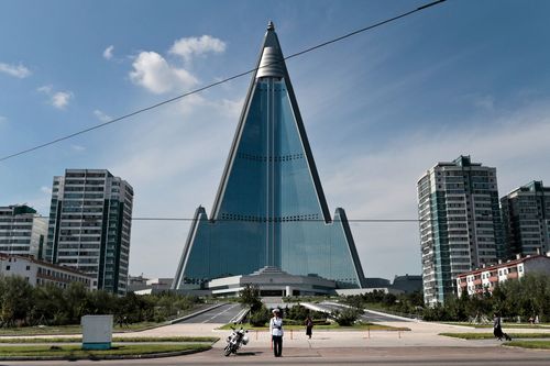 A traffic officer is dwarfed by the Ryugyong Hotel in Pyongyang, North Korea.