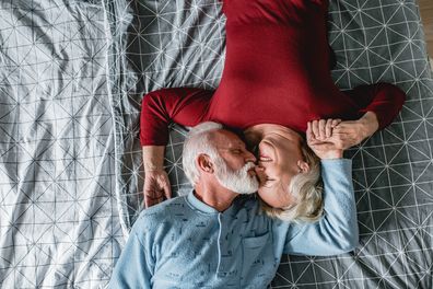 Old people in bed kissing