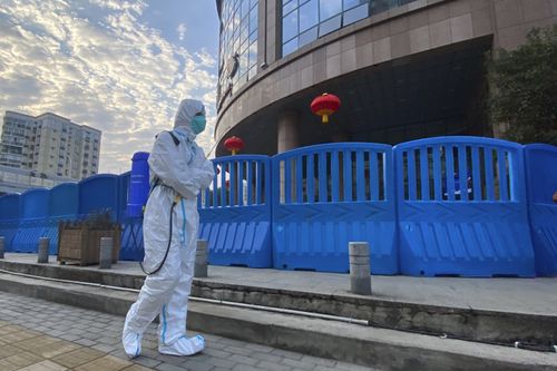 A worker in protectively overalls and carrying disinfecting equipment walks outside the Wuhan Central Hospital, China on  Feb. 6, 2021