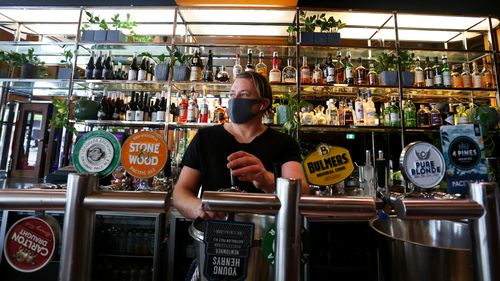 Hotel Manager Alex Marton prepares a bar area ahead of receiving patrons at the Kings Cross Hotel in Sydney's east.