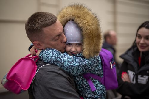 Ukrainian Nicolai, 41, says goodbye to his daughter Elina, 4, next to his wife Lolita, right, before boarding in a train bound for Poland fleeing from the war at the train station in Lviv, western Ukraine on Friday, April 15, 2022. (AP Photo/Emilio Morenatti)
