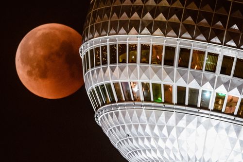 The red colored moon can be seen next to Berlin TV Tower in Berlin. Picture: AAP