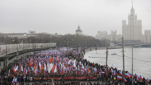 Marchers hold a poster of murdered Russian opposition veteran leader Boris Nemtsov with the words 'The heroes do not die. These bullets - in each of us'. (AAP)