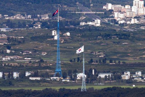 Steagurile nord-coreene, fundalul și Coreea de Sud, în față, flutură în vânt, așa cum este fotografiat din zona de graniță intercoreeană din Paju, Coreea de Sud, pe 9 august 2021. 
