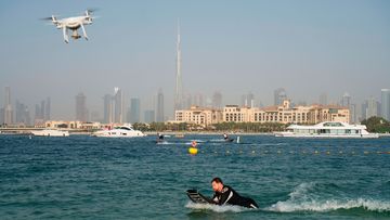A drone follows a man riding a motorized surfboard in Dubai, United Arab Emirates.
