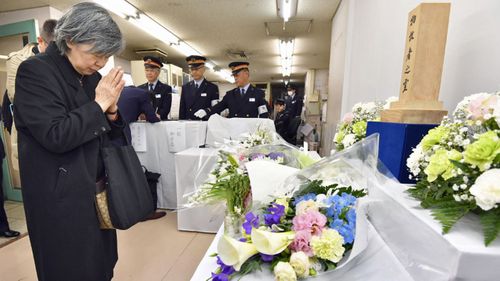 Shizue Takahashi, the wife of a subway worker killed in the March 20, 1995 sarin gas attack, prays after laying flowers on the stand set up at Kasumigaseki subway station in Tokyo on Tuesday. (AP).