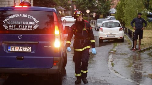 A firefighter walks by a hearse on the site of the attack in Cetinje, 36 kilometres west of Podgorica, Montenegro, Friday, Aug. 12, 2022. A man in Montenegro went on a shooting rampage after a family dispute, killing 11 people on the streets of a city before being shot dead in a gun battle with police. (AP Photo/Risto Bozovic)