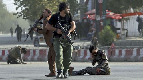 Afghan security personnel stand guard next to wounded comrades at the site of an attack near the Kabul International Airport, in Kabul, Afghanistan. (AAP)