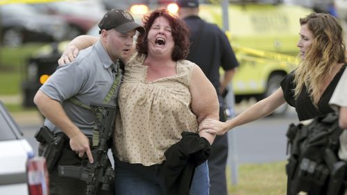 A women is escorted from the scene of the shooting at a software company Wisconsin. 