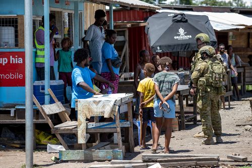Des soldats de l'armée australienne discutent avec des citoyens locaux à Honiara, aux Îles Salomon