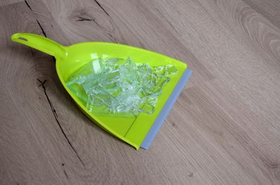 Green dustpan with broken glass