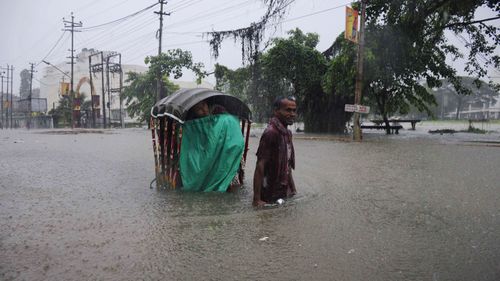 An Indian rickshaw puller transports a woman through a flooded street during a heavy downpour in Agartala. (AFP)