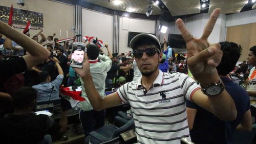 A protester displays an image of Moqtada al-Sadr on his smartphone inside the Iraqi parliament. (AFP)