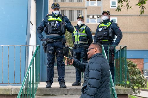 A man wanting to deliver groceries to a family who live at the Flemington Public housing flats speaks to Victoria Police in an effort to get access to the building.