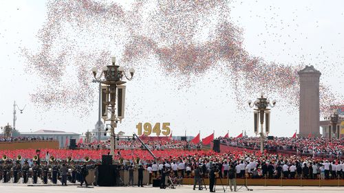 Balloons and doves are released into the air during the military parade.