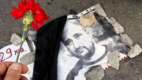 A picture of Russian journalist Arkady Babchenko with flower placed to pay tribute to him on the pavement of the Grand Moskvorestsky bridge, on the spot where Russian opposition politician Boris Nemtsov was shot dead near the Kremlin in Moscow. (AAP)