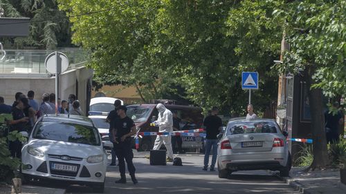 Police officers work at a crime scene close to the Israeli embassy in Belgrade, Serbia.