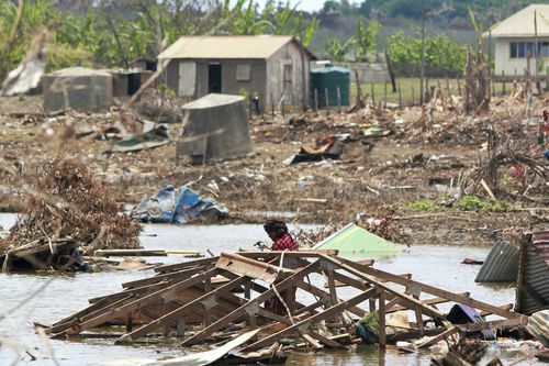 In this photo supplied by the Royal Australian Navy, a resident of Nomuka Island in Tonga clears debris on Feb. 26, 2022, following the Jan. 15 2022 eruption of the Hunga TongaHunga Ha'apai volcano and subsequent tsunami. Three months on from a devastating volcano and tsunami in Tonga, the AP checks in on how the island nation is recovering. The bill from the tsunami is estimated at some $90 million and GDP is expected to fall by more than 7% this year. The cleanup has been hindered by an intern