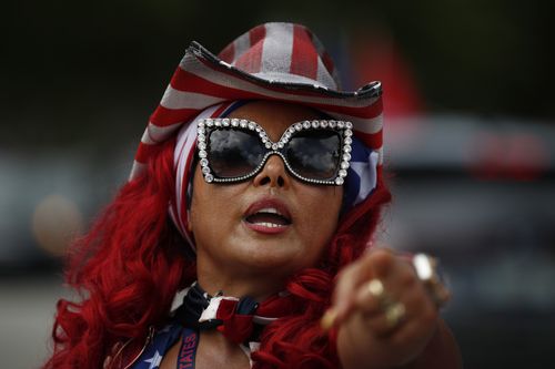 Susy Tylor, who calls herself one of the "Divas for Trump" greets other people arriving, as hundreds of cars gather ahead of the start of a car caravan in support of President Donald Trump, at Tropical Park in Miami