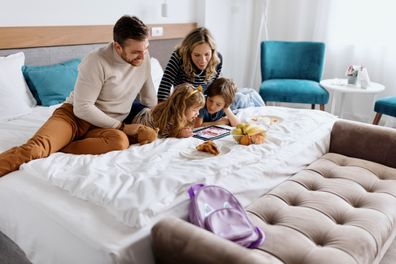 Happy family using digital tablet for video call with family while on vacation in a hotel