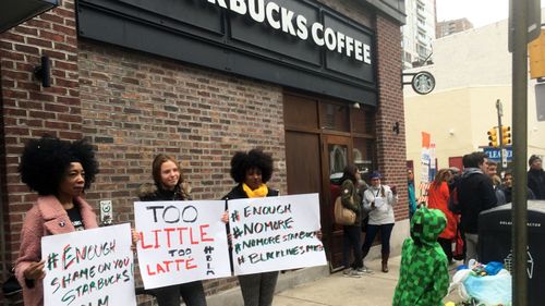 Protesters gather outside a Starbucks in Philadelphia where two black men were arrested Thursday after Starbucks employees called police to say the men were trespassing. (AAP)