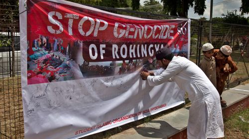 An Indian Muslim man puts his signature on a banner during a protest against the persecution of Myanmar's Rohingya Muslim minority. (AAP)