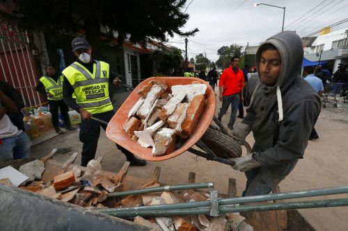 A man moves rubble taken from the Enrique Rebsamen school that collapsed after an earthquake in Mexico City. (AP)