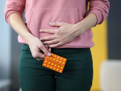 A woman holding a packet of birth control pills