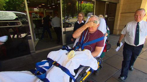 Andrew Thomas Philips hid his face as a paramedic wheeled him out of court today.