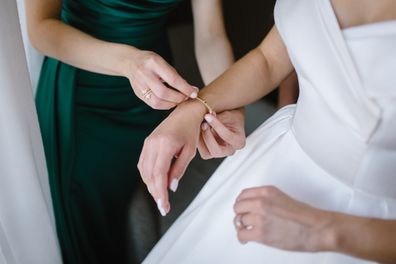 Bridesmaids helping gorgeous bride to dress up and get ready for her wedding ceremony.