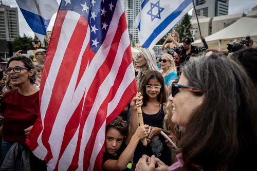 Um menino segura uma bandeira americana enquanto os israelenses reagem às notícias do acordo de paz de Gaza na Praça dos Reféns, em 9 de outubro de 2025, em Tel Aviv, Israel. 