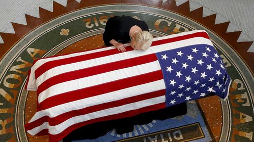 Cindy McCain rests her head on the casket of her late husband John.