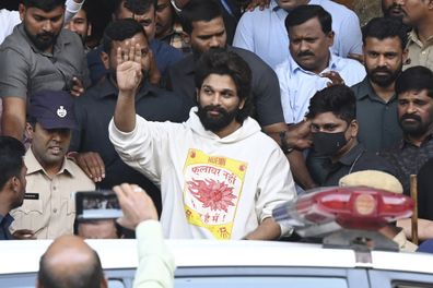 Indian Southern film actor Allu Arjun, center, greets his fans  in Hyderabad, India, Friday, Dec. 13, 2024, as he leaves a hospital where he was taken for medical checkup by policemen before arresting him after his appearance at a film screening allegedly led to a crush of fans in which a woman died. (AP Photo)