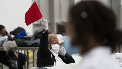 An election inspector waves a flag to call for assistance as ballots are counted into the early morning hours in Detroit, Michigan.