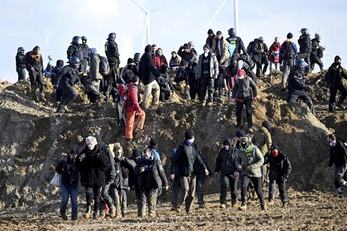  Activists and coal opponents walk along the demolition edge of the Garzweiler II opencast lignite mine during a protest by climate activists after the clearance of Luetzerath, with police officers standing in between in Erkelenz, Germany, Tuesday, Jan. 17, 2023.  