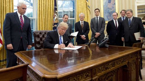 Steve Bannon (far left) as Donald Trump signs an executive order. (AP)