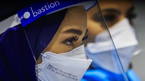 Health workers look on at the Histopath pre-departure COVID testing clinic at Sydney International airport