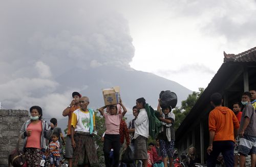 Villagers carry their belongings during an evacuation following the eruption of Mount Agung. (AAP)