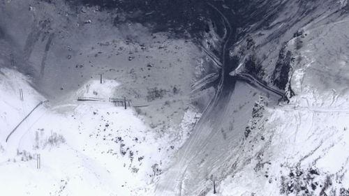 Aerial images showed sections of the snowy mountain covered in dark ash. (AP)
