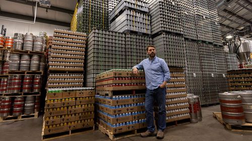 Jeff Ware, president of Resurgence Brewing Company, poses for a portrait near a stockpile of aluminum cans, which are sourced from Canada.