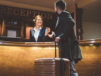 Man arriving in hotel and receiving keys from his room after check-in.