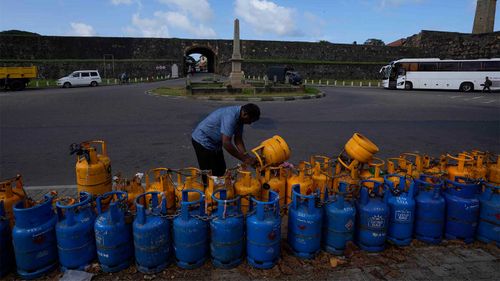 A Sri Lankan man padlocks his gas canister as he places it in a queue to get it refilled.