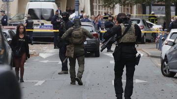 Elite police officers of the RAID squad patrol after a man armed with a knife killed a teacher and wounded two others at a high school in northern France, Friday, Oct. 13, 2023 in Arras.  