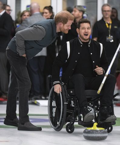 Prince Harry, the Duke of Sussex, jokes with singer Michael Buble, right, as he prepares to take a shot  during an Invictus Games wheelchair curling training camp in Vancouver, British Columbia, Friday, Feb. 16, 2024. (Darryl Dyck/The Canadian Press via AP)