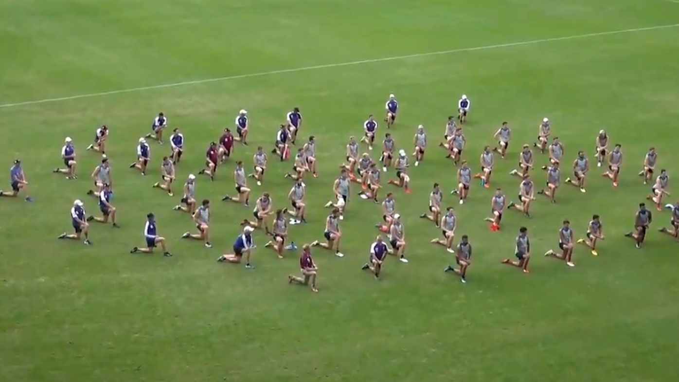 Brisbane Lions players and staff take a knee